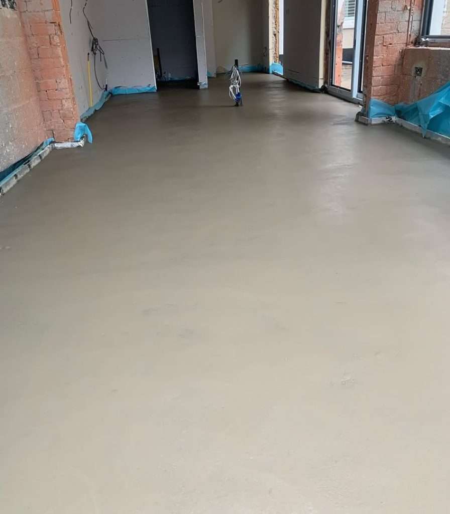 Sand and Cement Screed floor in an open-plan room with brick walls